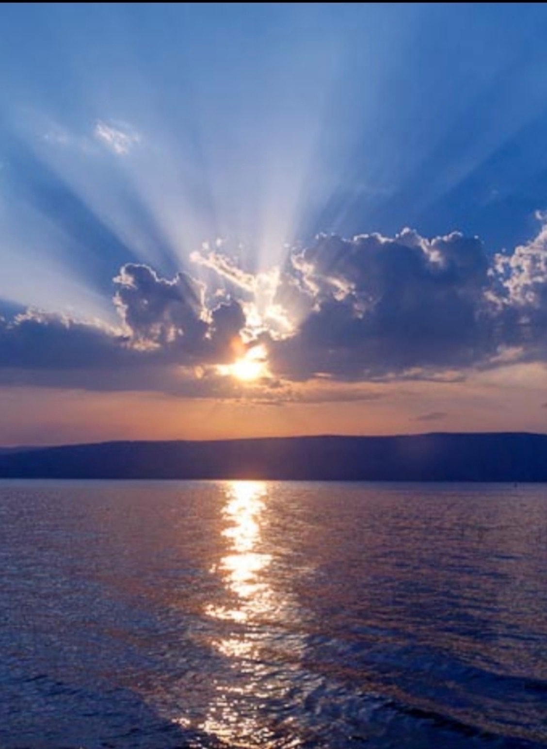 Sunlight breaking through clouds over lake